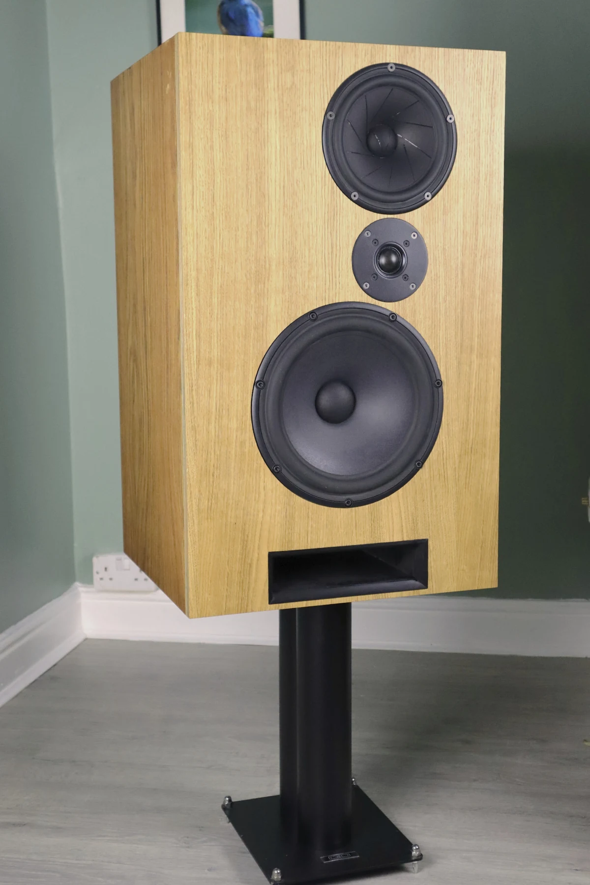 Angled view of a Cwen loudspeaker showing the real wood front and darker side veneer